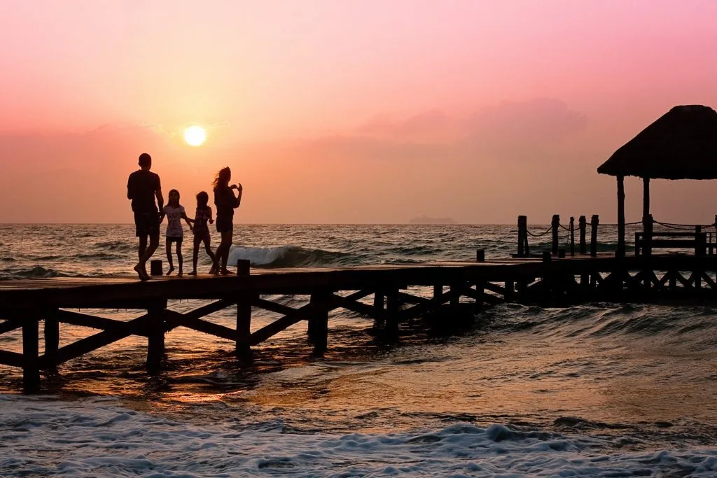 A family silhouetted on a pier at sunset